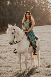 woman in blue tank top riding white horse during daytime